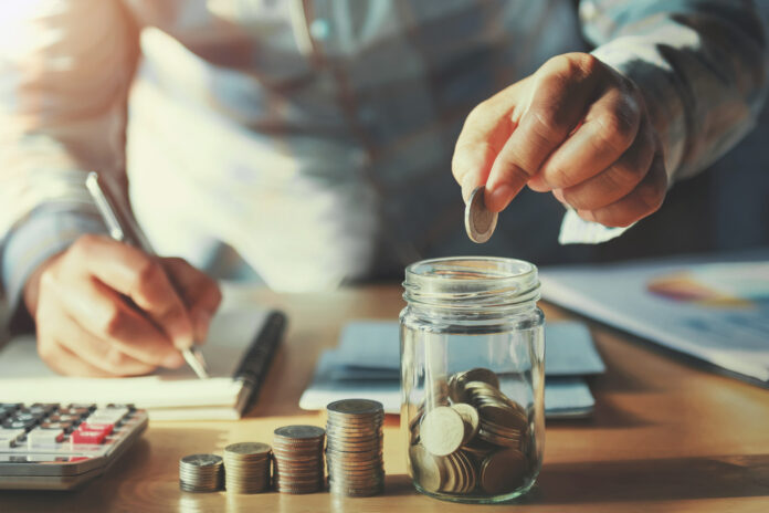 businessman saving money concept hand holding coins putting in peníze