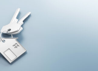 Investície do nehnuteľností vs. fondy REIT: Ako vlastniť nehnuteľnosti bez starostí s nájomníkmi? White house-shaped keychain on a light blue gradient background, symbolizing home ownership