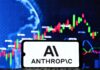 Anthropic zaplatí 1,5 miliardy dolárov za urovnanie sporu o autorské práva Smartphone screen showing 'AI ANTHROPIC' in front of a blue stock chart background.