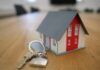 Hypotéka vs. nájom v ČR a SR: Čo sa reálne oplatí pri súčasných úrokových sadzbách? Miniature house model with a set of keys on a wooden table, representing home ownership or real estate knowledge.