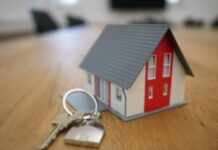 Hypotéka vs. nájom v ČR a SR: Čo sa reálne oplatí pri súčasných úrokových sadzbách? Miniature house model with a set of keys on a wooden table, representing home ownership or real estate knowledge.